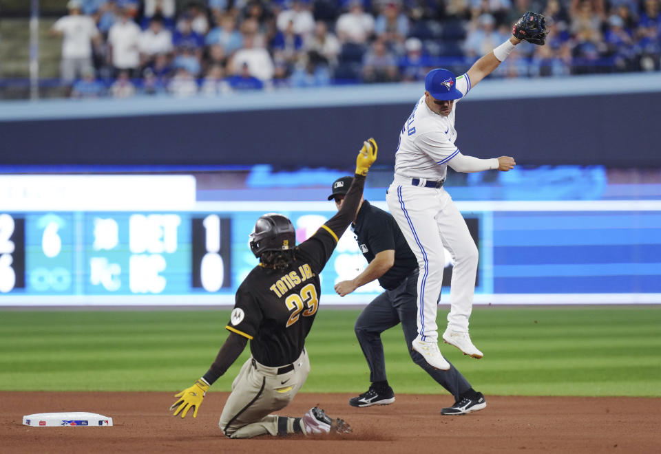 San Diego Padres' Fernando Tatis Jr. (23) slides safely into second base with a double as Toronto Blue Jays second baseman Whit Merrifield (15) jumps for the throw during the seventh inning of a baseball game Wednesday, July 19, 2023, in Toronto. (Chris Young/The Canadian Press via AP)