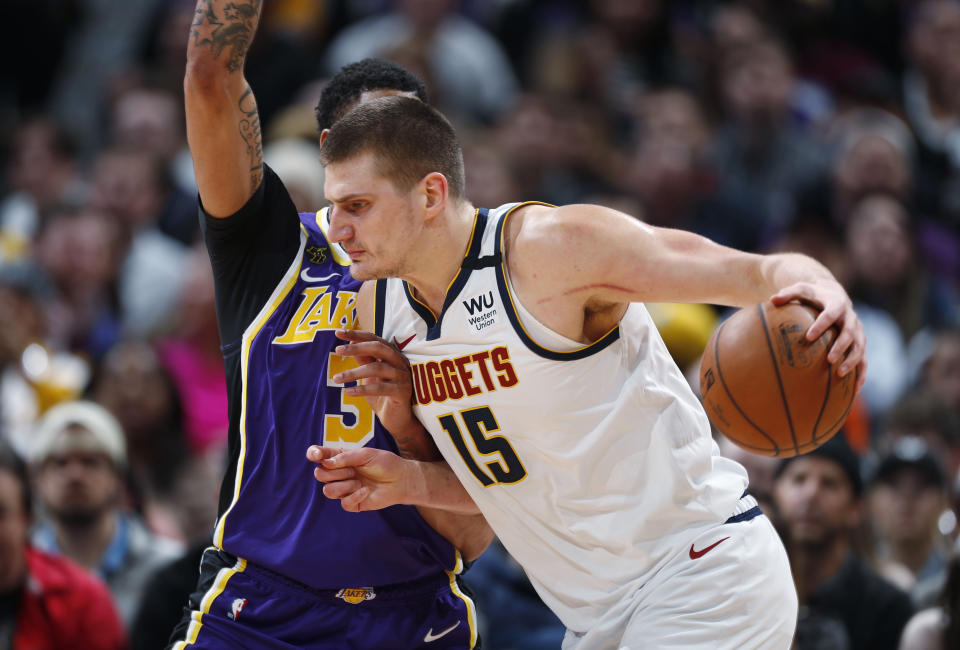 FILE - In this Feb. 12, 2020, file photo, Denver Nuggets center Nikola Jokic drives as Los Angeles Lakers forward Anthony Davis defends during the first half of an NBA basketball game in Denver. A person with knowledge of the situation says Jokic has tested positive for the coronavirus and is quarantining in his native Serbia. (AP Photo/David Zalubowski, File)