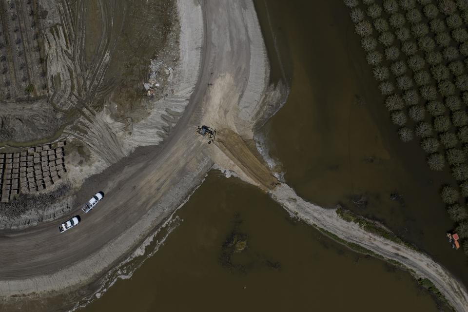 Heavy equipment reinforces levees in preparation of possible flooding as farmland in the Tulare Lake Basin is submerged in water in Corcoran, Calif., Thursday, April 20, 2023, after more than a dozen atmospheric rivers dumped record-setting rain and snowfall. Officials want to raise the levee another 3.5 feet (1 meter), city officials said. (AP Photo/Jae C. Hong)