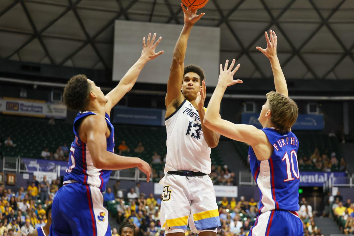 Marquette forward Oso Ighodaro shoots between Kevin McCullar Jr. (15) and Johnny Furphy (10) of the Kansas Jayhawks during the first half of their game in the semifinals of the Allstate Maui Invitational at SimpliFi Arena on Nov. 21, 2023, in Honolulu, Hawaii.
