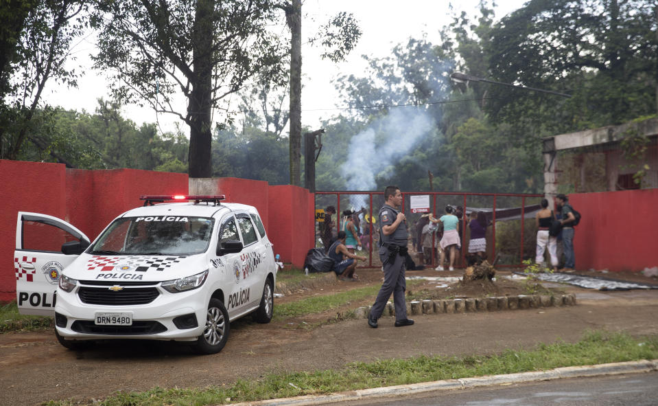 A police officer walks outside the permitter of a development project for apartment buildings by real estate company Tenda, where Guarani Mbya indigenous protest the project next to their community's land in Sao Paulo, Brazil, Thursday, Jan. 30, 2020. The tension between a builder with projects in nine Brazilian states and a 40-family indigenous community is a microcosm of what’s playing out elsewhere in the country. (AP Photo/Andre Penner)