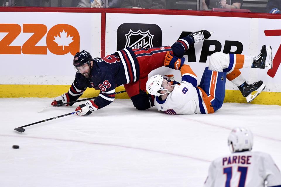 New York Islanders' Noah Dobson (8) is checked by Winnipeg Jets' Sam Gagner (89) during first-period NHL hockey game action in Winnipeg, Manitoba, Sunday, Feb. 26, 2023. (Fred Greenslade/The Canadian Press via AP)