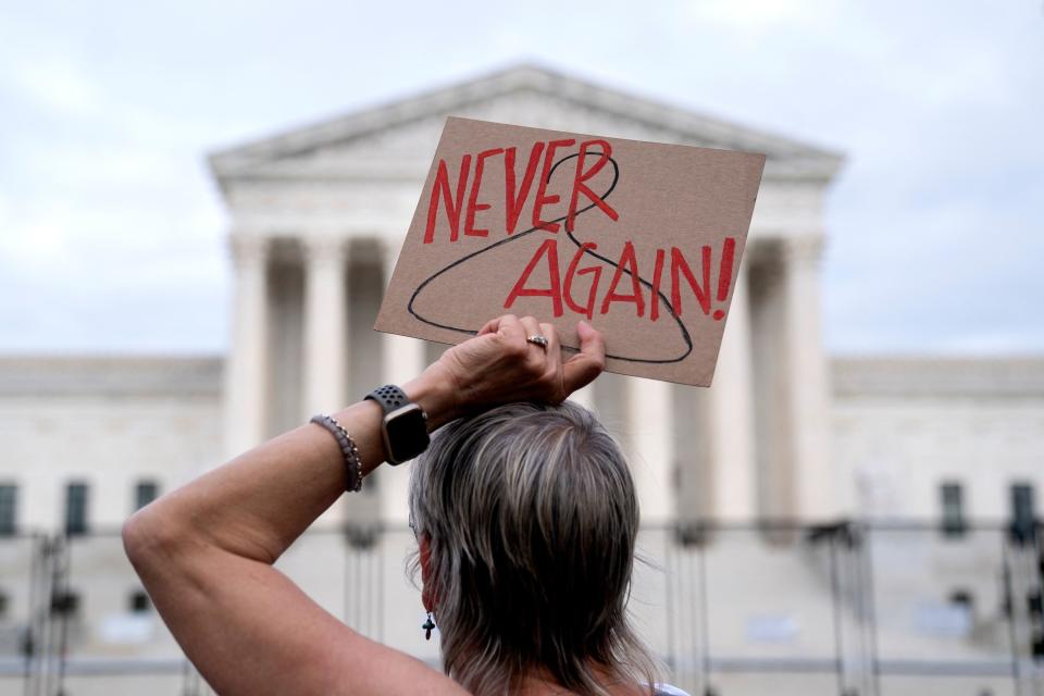 Pro abortion protester holding a sign saying never again