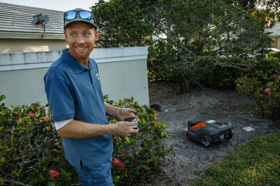 Tyler Reiter, owner of Florida Image Landscaping, Inc., shows off a Husqvarna robot grass mowing machine at Bear Island gated community in West Palm Beach, Fla., on August 10, 2023