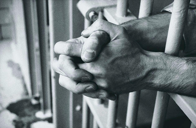 File photo of hands resting on prison bars (Dick Luria/Thinkstock)