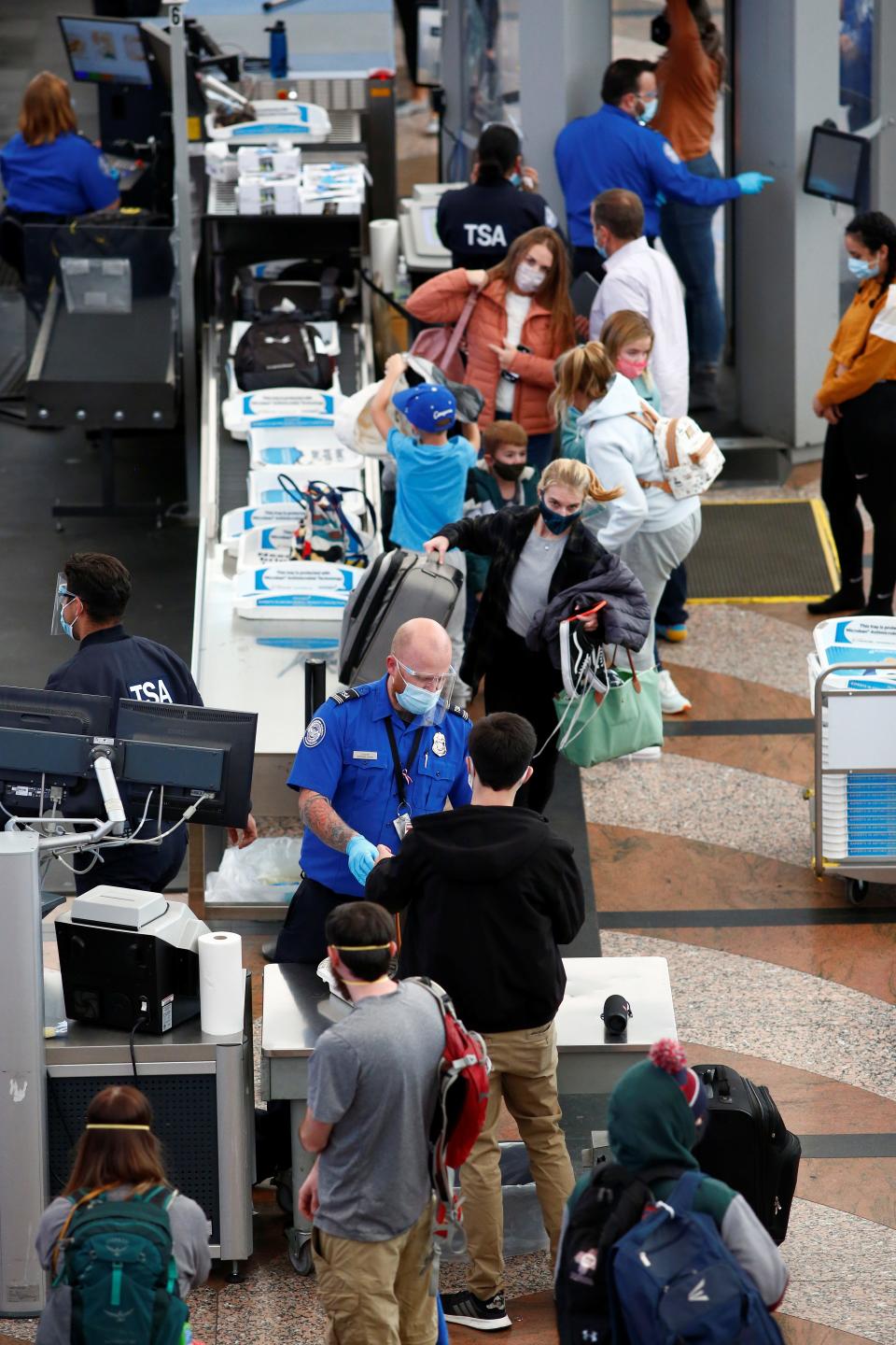 Travelers wearing protective face masks to prevent the spread of the coronavirus disease (COVID-19) go through security before boarding a flight at the airport in Denver, Colorado, U.S., November 24, 2020.