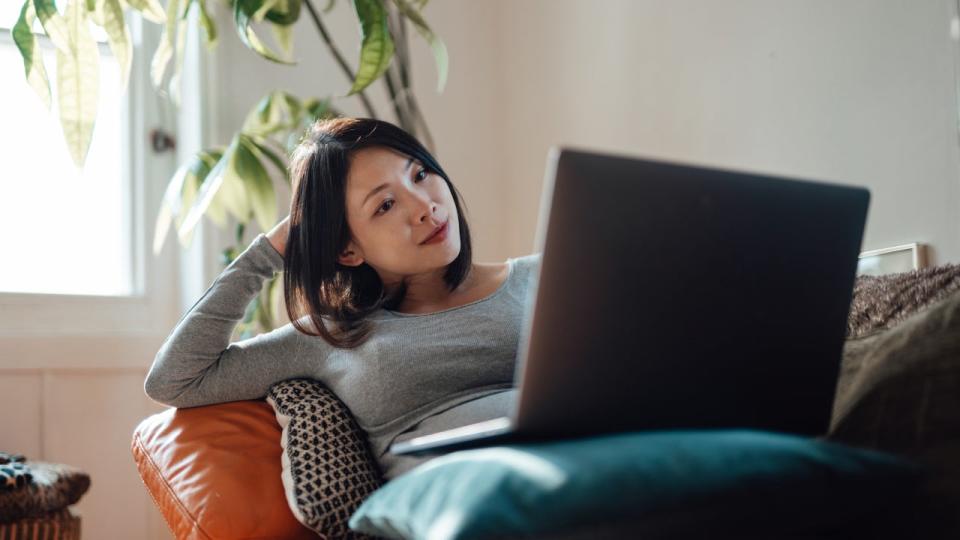 Young pregnant businesswoman at home office, working with laptop on sofa