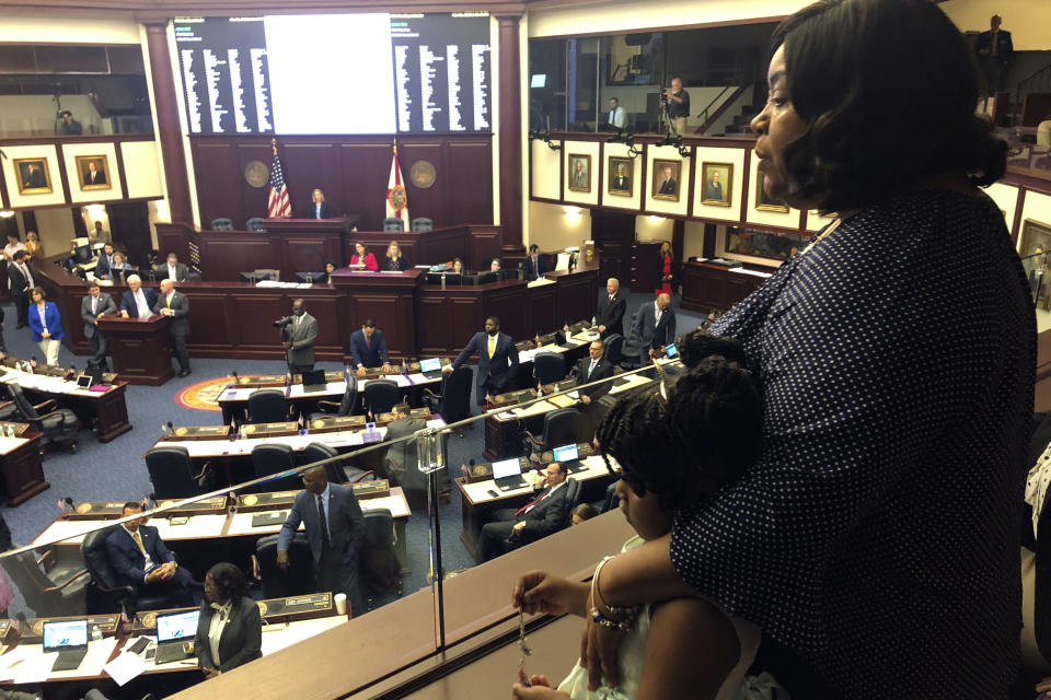Meralyn Kirkland holds her granddaughter Kaia Rolle as legislators work on the House floor, Wednesday, March 4, 2020, in Tallahassee, Fla. Florida lawmakers rallied behind a 6-year-old Rolle who was zip-tied at school and arrested last fall, and on Wednesday inserted an amendment into a school safety bill to require authorities to disclose their policies and procedures for arresting children under 10 years old. The scene generated public outrage when footage from a police body camera showed the crying young girl pleading with the arresting officer for "a second chance." (AP Photo/Bobby Caina Calvan)