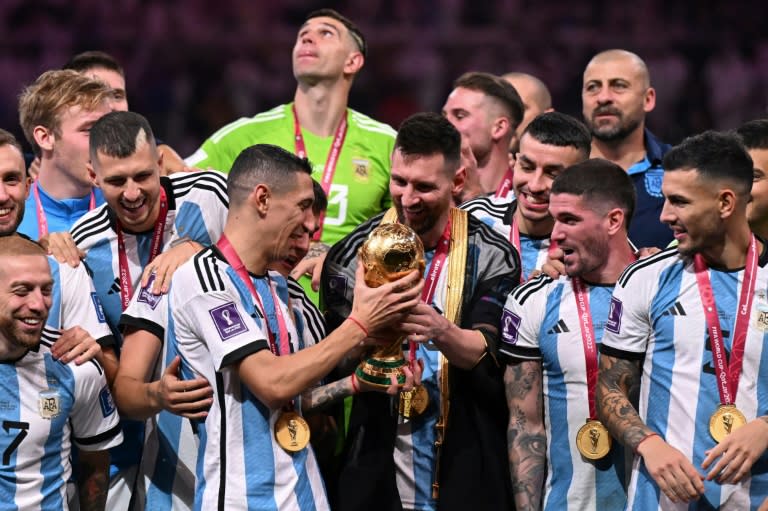 Ángel Di Maria recibe de Lionel Messi el trofeo de la Copa Mundial de fútbol tras la victoria de Argentina ante Francia en la final del Mundial-2022 el 18 de diciembre de 2022 en Lusail, norte de Doha (Kirill KUDRYAVTSEV)