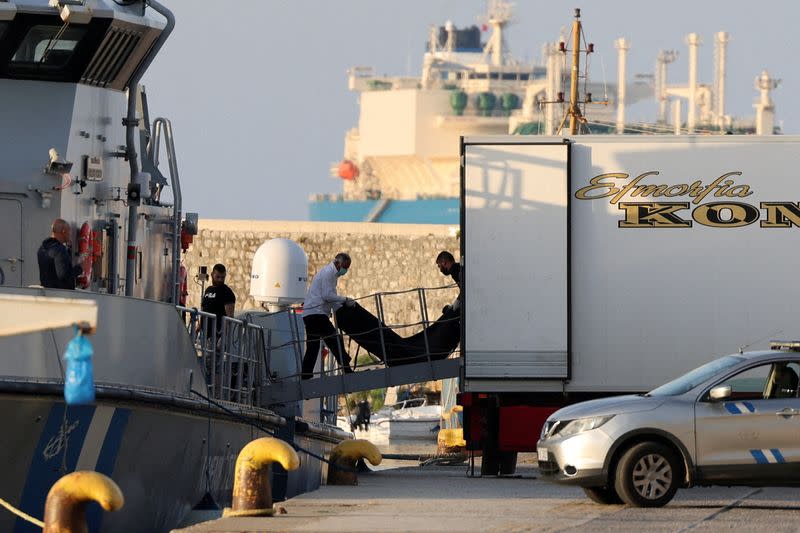 FILE PHOTO: Men transfer body bags carrying migrants who died after their boat capsized in the open sea off Greece, onboard a Hellenic Coast Guard vessel at the port of Kalamata