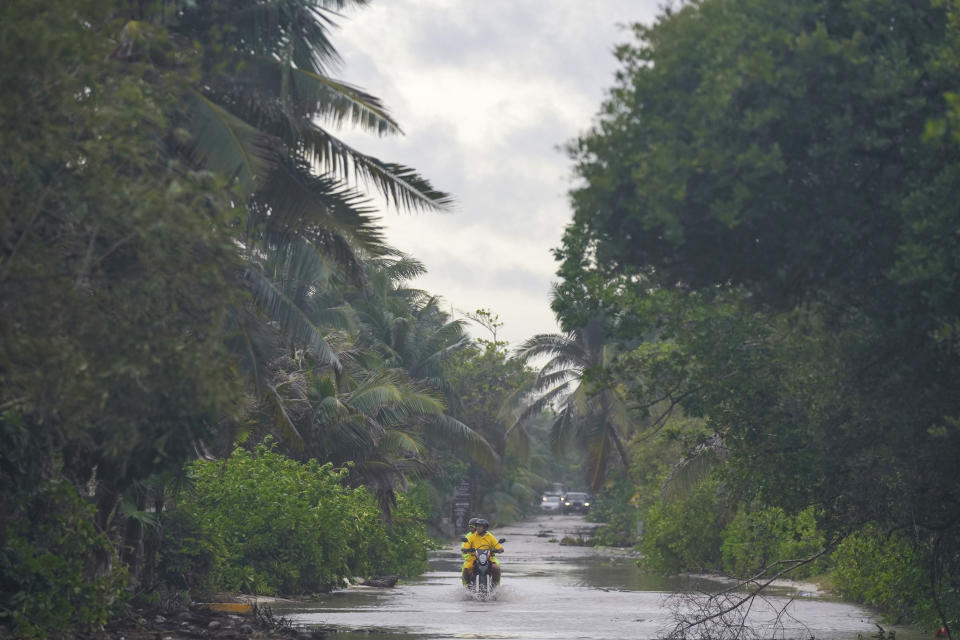 A motorcyclist rides throw a street flooded by heavy rains from Hurricane Beryl, in Tulum, Mexico, Friday, July 5, 2024. (AP Photo/Fernando Llano)