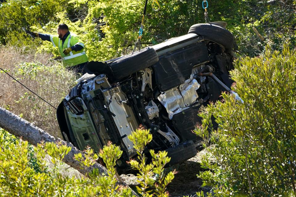 Workers move a vehicle on its side after a rollover accident involving golfer Tiger Woods Tuesday, Feb. 23, 2021, in the Rancho Palos Verdes section of Los Angeles. Woods suffered leg injuries in the one-car accident and was undergoing surgery, authorities and his manager said.