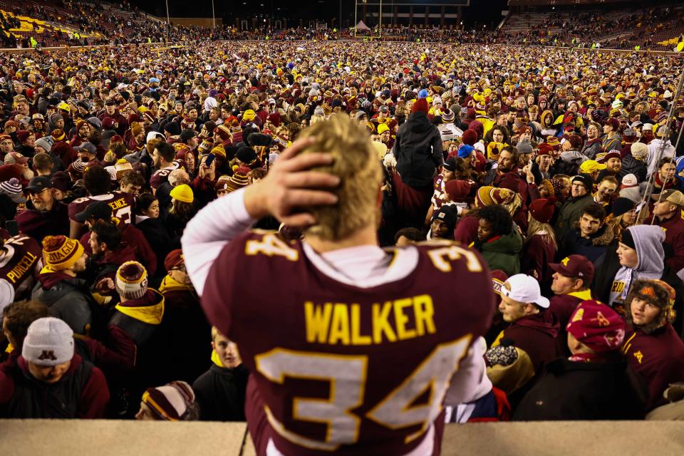 Gophers place kicker Brock Walker watches fans rush the field.