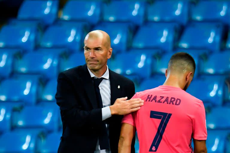 El entrenador francés del Real Madrid Zinedine Zidane (L) toca el delantero belga del Real Madrid Eden Hazard mientras abandona el terreno de juego después de ser sustituido durante los octavos de final de la Liga de Campeones de la UEFA el segundo partido de fútbol entre el Manchester City y el Rea