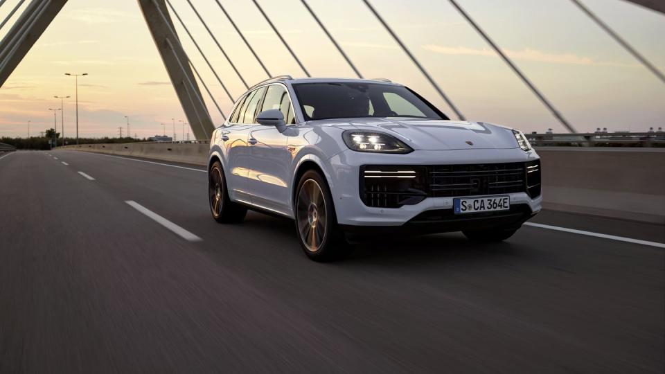 2024 porsche cayenne turbo e hybrid driving over a bridge at dusk