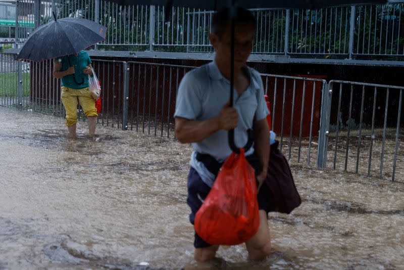 Varias personas se abren paso a través de una zona inundada tras las fuertes lluvias, en Hong Kong, China