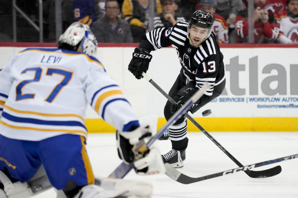 New Jersey Devils center Nico Hischier (13) takes a shot on Buffalo Sabres goaltender Devon Levi (27) during the second period of an NHL hockey game, Tuesday, April 11, 2023, in Newark, N.J. (AP Photo/John Minchillo)