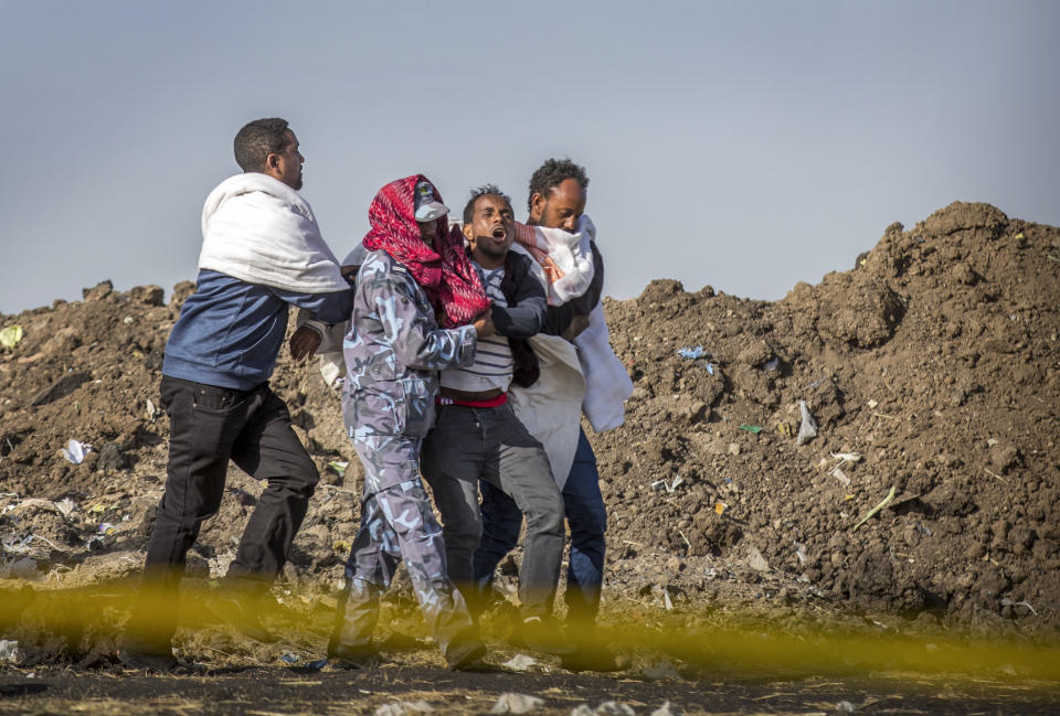 FILE - In tis Wednesday, March 13, 2019 file photo, a grieving relative who lost his wife in the crash is helped by a member of security forces and others at the scene where the Ethiopian Airlines Boeing 737 Max 8 crashed shortly after takeoff on Sunday killing all 157 on board, near Bishoftu, or Debre Zeit, south of Addis Ababa, in Ethiopia. Pilots of the Ethiopian Airlines flight encountered problems with their new Boeing jetliner from nearly the moment they roared down the runway and took off. Ethiopian authorities issued a preliminary report Thursday, April 4, 2019, on the March 10 crash. (AP Photo/Mulugeta Ayene, File)