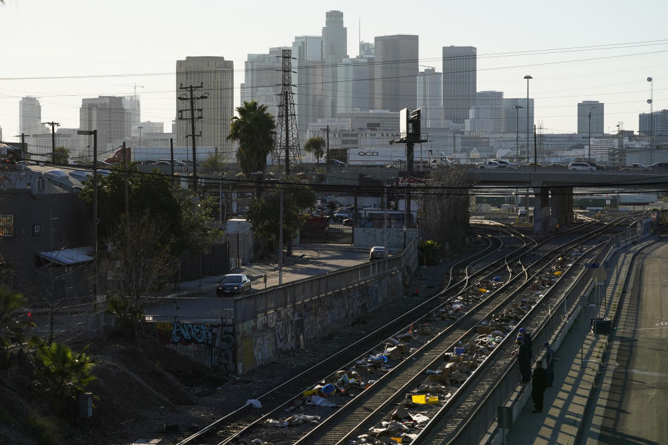 Men look over a railing at a Union Pacific railroad site on Thursday, Jan. 20, 2022, in Los Angeles. Gov. Gavin Newsom on Thursday promised statewide coordination in going after thieves who have been raiding cargo containers aboard trains nearing downtown Los Angeles for months, leaving the tracks blanketed with discarded boxes. . (AP Photo/Ashley Landis)