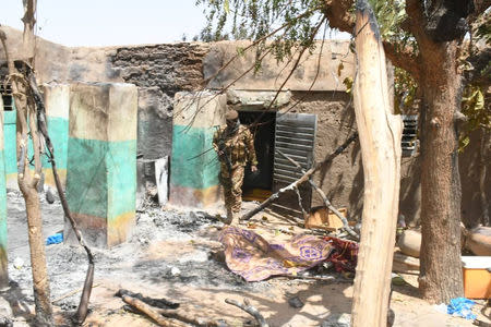 A soldier walks amid the damage after an attack by gunmen on Fulani herders in Ogossagou, Mali March 25, 2019. Picture taken March 25, 2019. Malian Presidency/Handout via Reuters