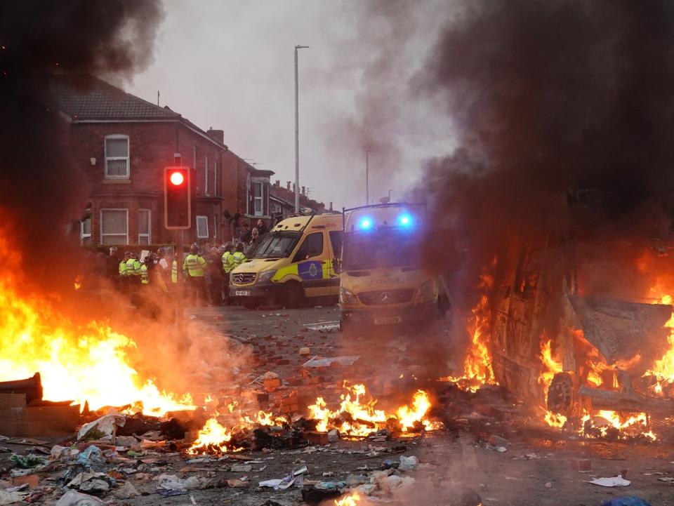 Riot police hold back protesters near a burning police vehicle after disorder broke out on 30 July in Southport (Getty)