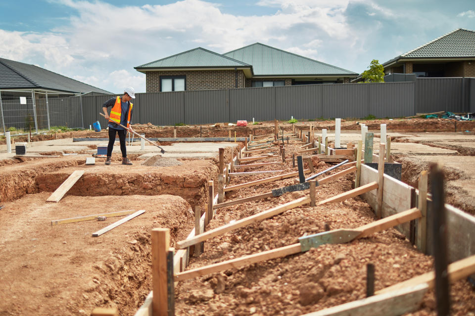 Male worker working at construction site on a new housing estate.