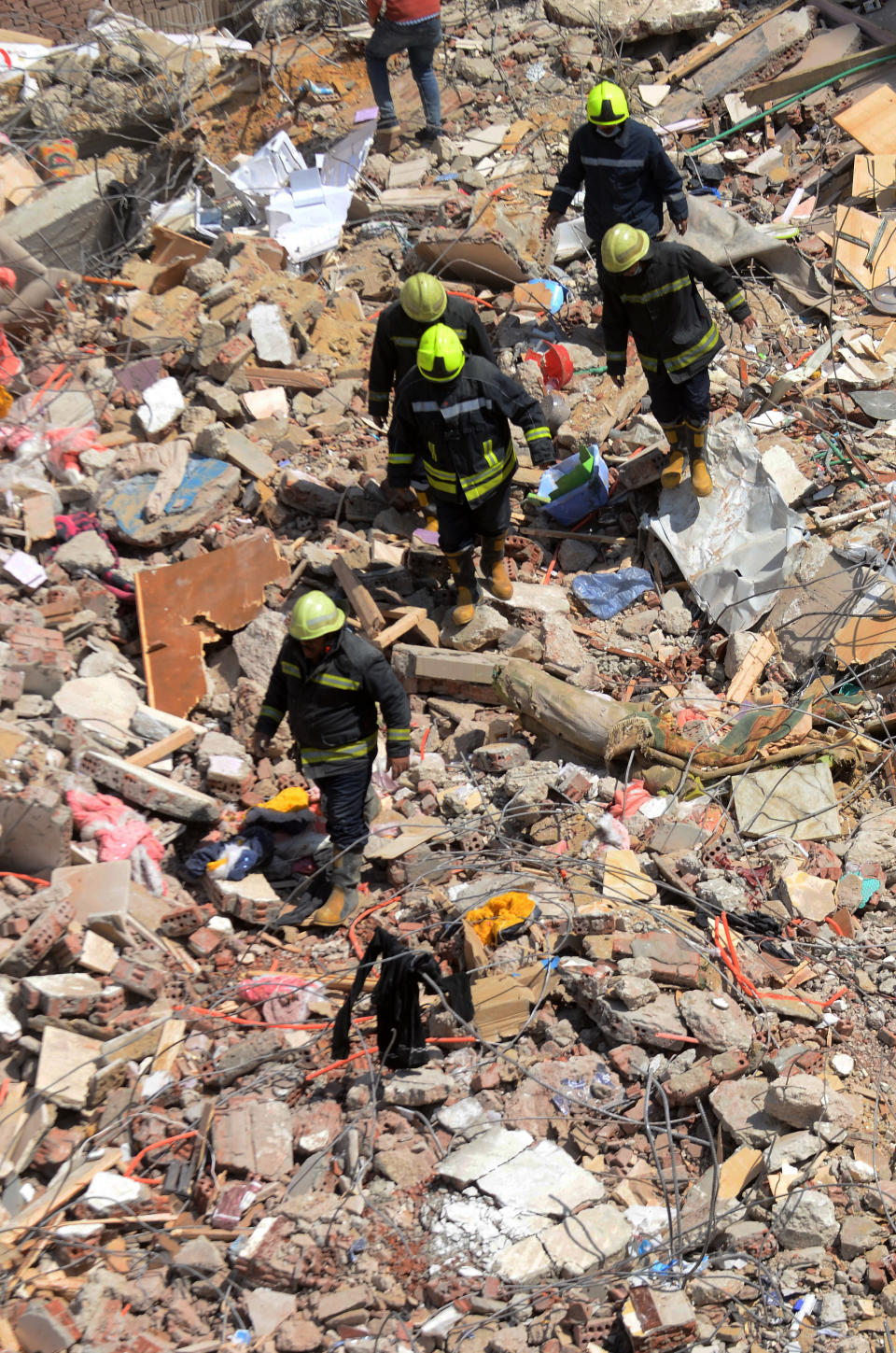 Rescuers look for victims on the rubble of a collapsed apartment building in the el-Salam neighborhood, in Cairo, Egypt, Saturday, March 27, 2021. A nine-story apartment building collapsed in the Egyptian capital early Saturday, killing at several and injuring about two dozen others, an official said. (AP Photo/Tarek wajeh)