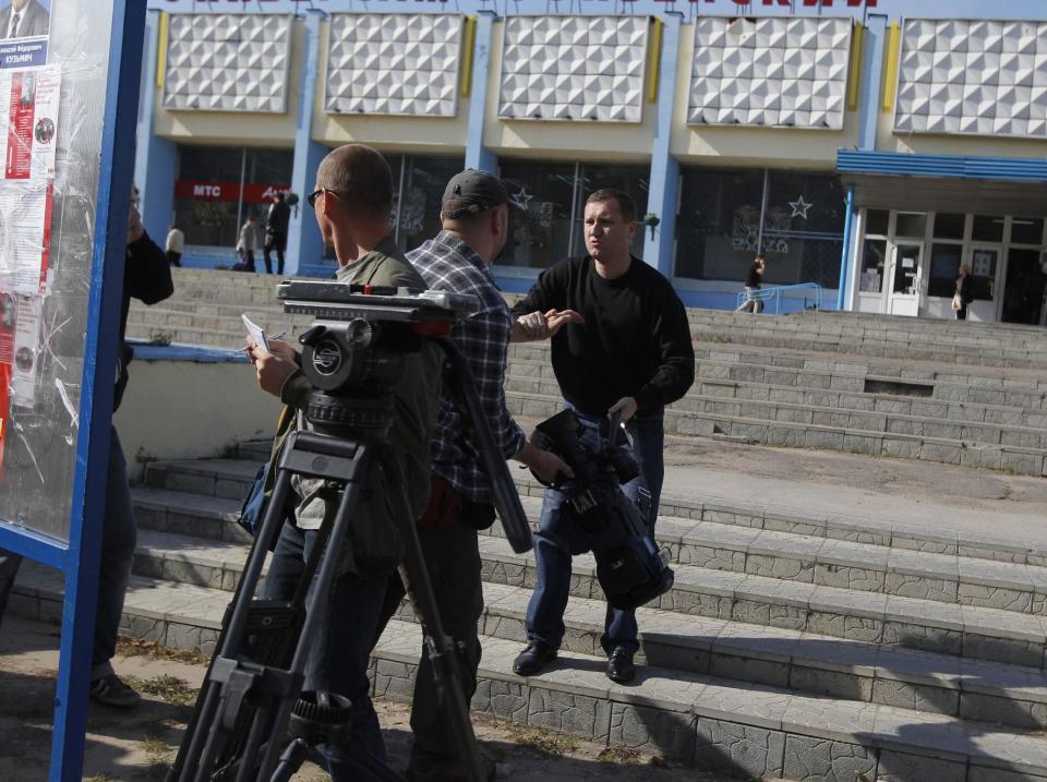 Belarus plainclothes security officer, right, holds a camera, he took away from a journalist, during in Minsk , Tuesday, Sept. 18, 2012. Associated Press photographer Sergei Grtts was beaten and briefly detained by plainclothes security officers in the Belarusian capital. Sergei Grits says he was among eight journalists covering a protest by four opposition activists calling for a boycott of this weekend's parliamentary elections when plainclothes security officers attacked them in downtown Minsk.(AP Photo/Sergei Grits)