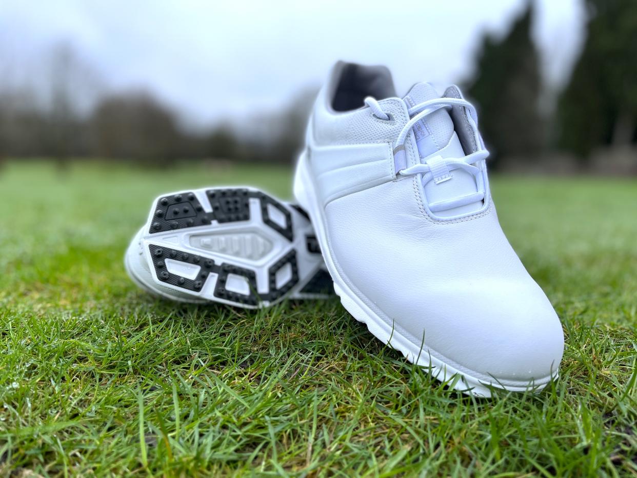 FootJoy Pro SL 2022 shoes lying on grass, white golf shoes