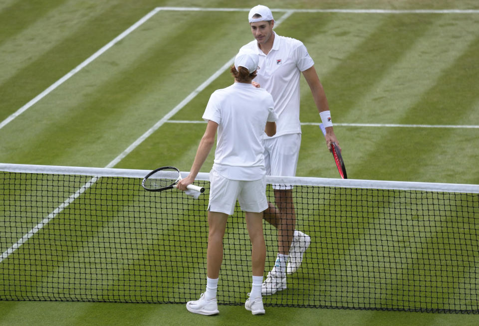 Italy's Jannik Sinner, front, shakes hands with John Isner of the US after beating him in their men's singles third round match on day five of the Wimbledon tennis championships in London, Friday, July 1, 2022. (AP Photo/Kirsty Wigglesworth)