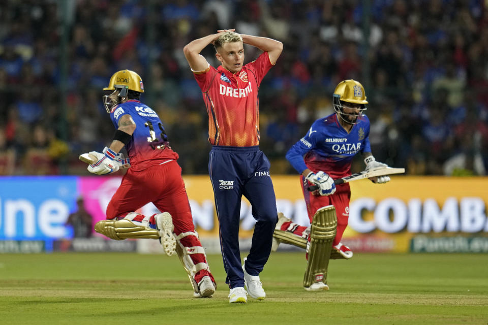 Punjab Kings' Sam Curran, center, reacts after Royal Challengers Bengaluru's Virat Kohli, left, played a shot on his delivery during the Indian Premier League cricket match between Royal Challengers Bengaluru and Punjab Kings in Bengaluru, India, Monday, March 25, 2024. (AP Photo/Aijaz Rahi)