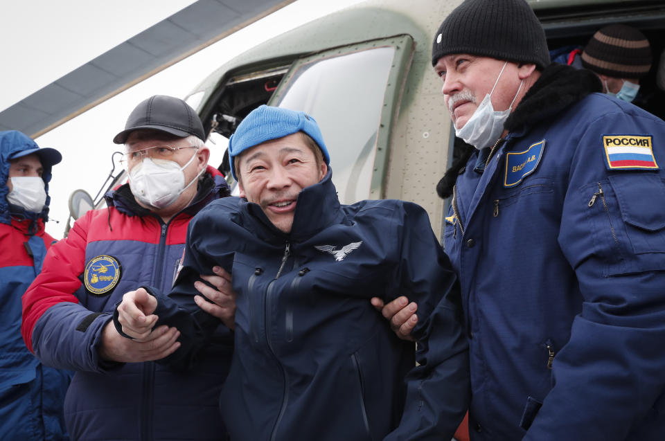 Space flight participant Japanese entrepreneur Yusaku Maezawa is assisted as he disembarks from a helicopter as he arrives at the airport after returning from the International Space Station on the Soyuz MS-20 space capsule, in Zhezkazgan, Kazakhstan, Monday, Dec. 20, 2021. A Japanese billionaire, his producer and a Russian cosmonaut safely returned to Earth on Monday after spending 12 days on the International Space Station. (Shamil Zhumatov/Pool Photo via AP)