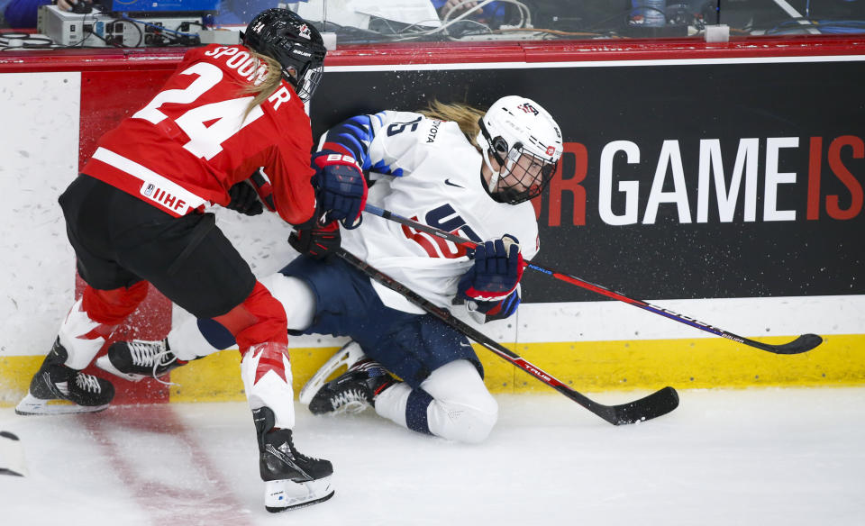 Canada's Natalie Spooner, left, checks United States' Savannah Harmon during the second period of the IIHF hockey women's world championships title game in Calgary, Alberta, Tuesday, Aug. 31, 2021. (Jeff McIntosh/The Canadian Press via AP)