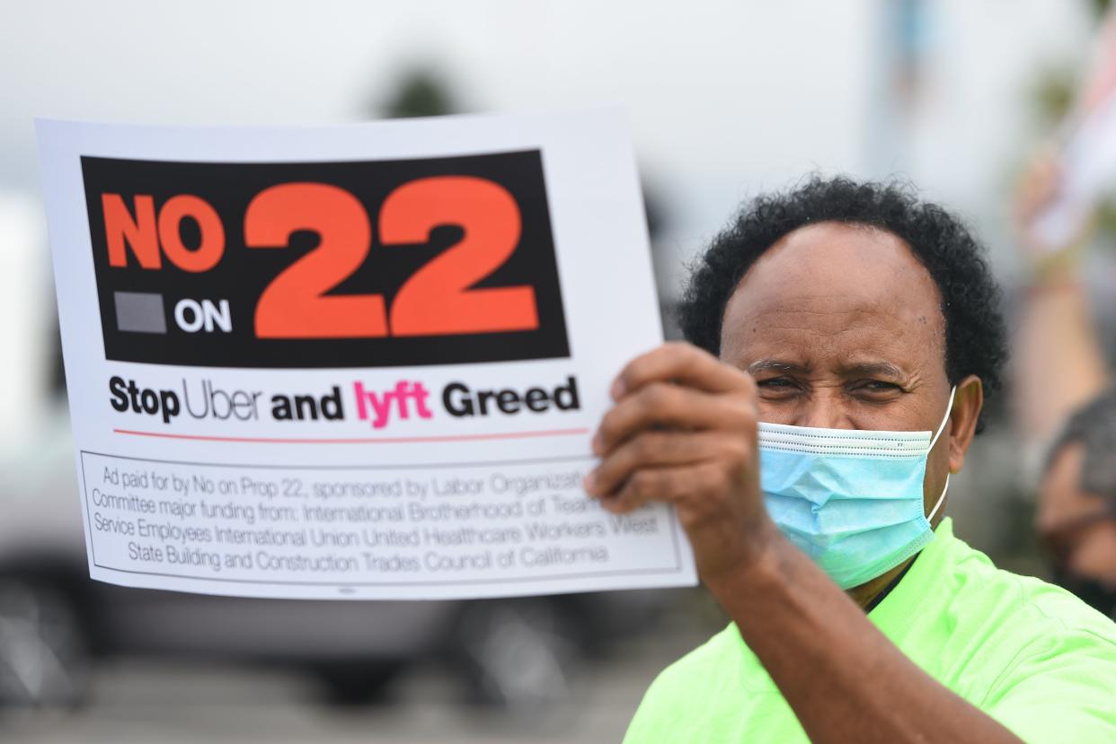 A rideshare driver holds up a sign supporting a no vote on Prop 22 in Oakland, California on October 9, 2020. - Ahead of a referendum that could upend the whole gig economy, Uber driver Karim Benkanoun says his relationship with the rideshare giant must stop being a one-way street. "If youre a driver with Uber or Lyft, you're nothing," said Benkanoun as he speaks of how he will vote in California's Proposition 22 referendum. (Photo by JOSH EDELSON / AFP) (Photo by JOSH EDELSON/AFP via Getty Images)