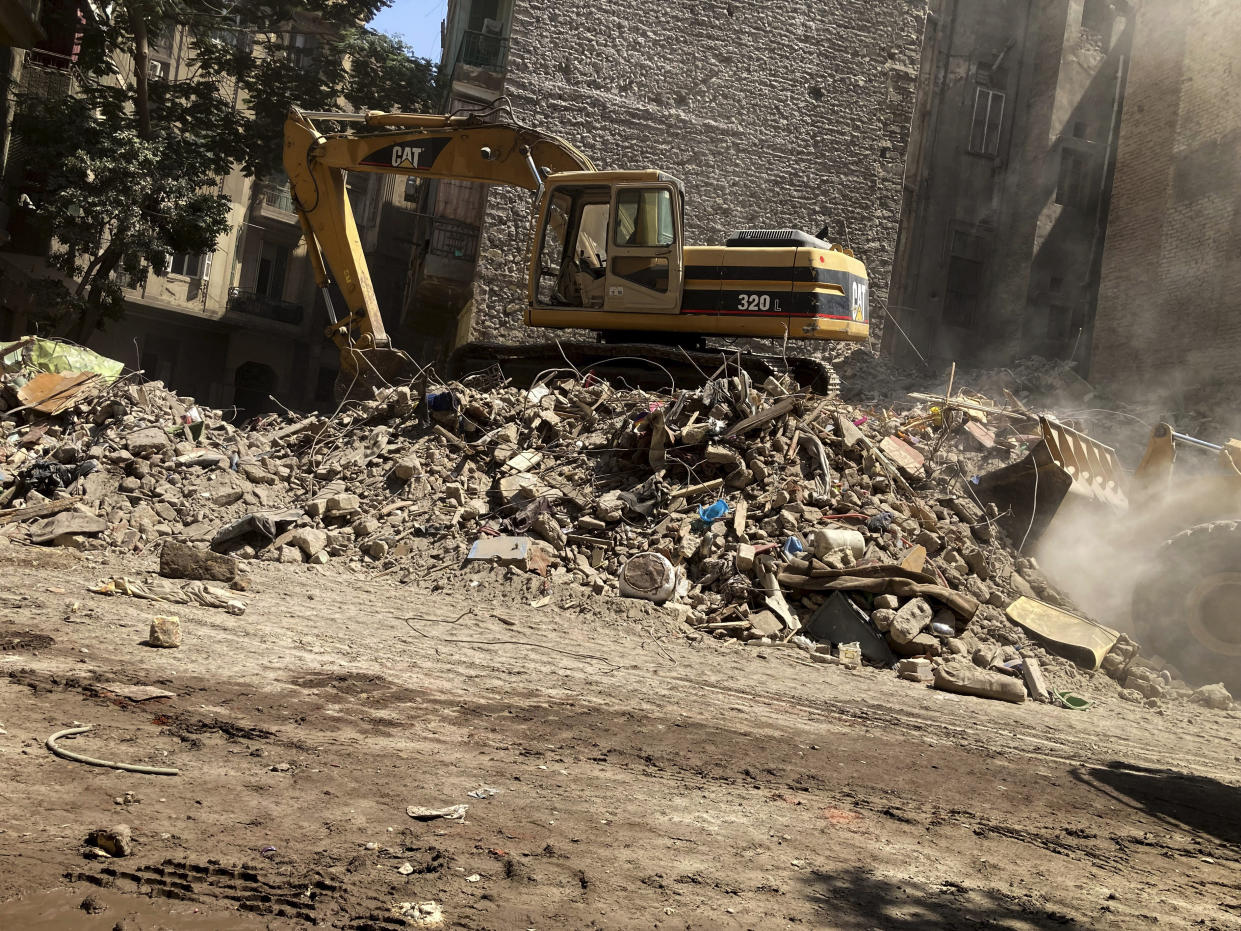 A bulldozer removes debris of a building that collapsed in El-Weili neighborhood, Cairo, Egypt, Friday, June 17, 2022. A five-story apartment building collapsed in the Egyptian capital early Friday, killing numerous people according to officials. (AP Photo/Ahmed Hatem)