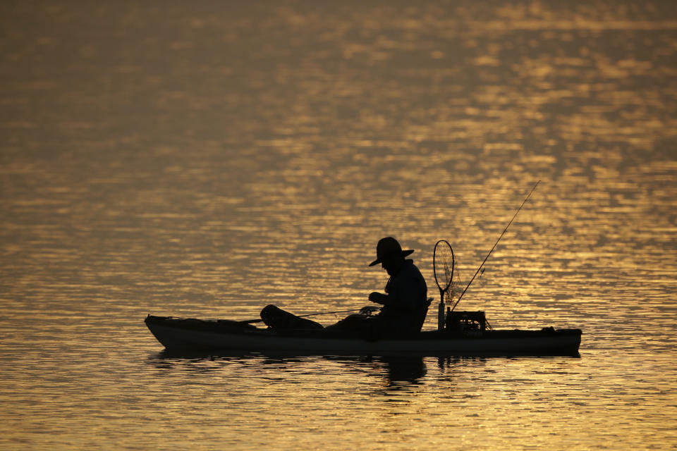 A man fishes in the Indian River Lagoon at sunrise Saturday, May 30, 2020, at Titusville, Fla. as he waits for the launch of the SpaceX Falcon 9, with Dragon crew capsule on top of the rocket. Two astronauts are set to fly on the SpaceX Demo-2 mission to the International Space Station scheduled for launch from the Kennedy Space Center in Cape Canaveral, Fla. For the first time in nearly a decade, astronauts will blast into orbit aboard an American rocket from American soil, a first for a private company. (AP Photo/Charlie Riedel)