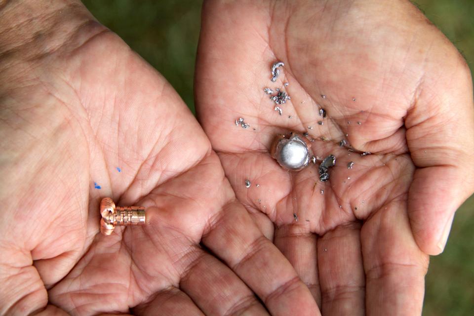 A participant in a bullet comparison holds the recovered pieces of a copper bullet (left) and a lead-based bullet. The copper bullet mushroomed on impact and retained all of its weight, while the lead-based bullet expanded and splintered into dozens of smaller pieces. Photo taken by Paul A. Smith.
