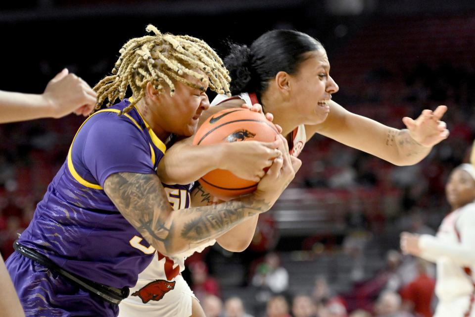 LSU guard Kateri Poole, left, and Arkansas guard Chrissy Carr, right, fight for control of the ball during an NCAA basketball game on Thursday, Dec. 29, 2022, in Fayetteville, Ark. (AP Photo/Michael Woods)