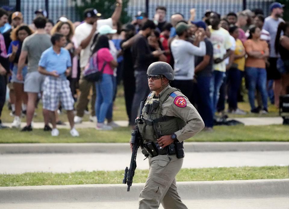 A law enforcement officer walks as people are evacuated from a shopping center where a shooting occurred Saturday, May 6, 2023, in Allen, Texas. 