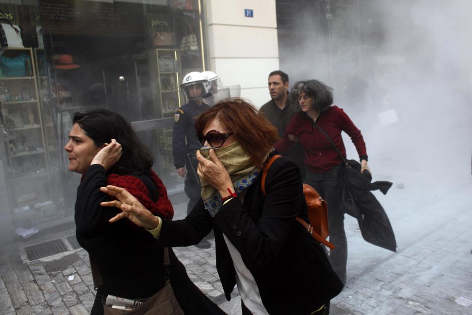 Demonstrators and pedestrians run to avoid tear gas during a protest against the opening of shops on Sundays and the extension of working hours, in Athens' Ermou shopping street, on Sunday, April 13 2014. Fitch ratings agency warned the successful bond issue didn't mean an end to Greece's financial problems. In a report Friday it said the issue showed the country's progress but doesn't mean it will be able to finance itself on its own when the bailout program ends later this year. (AP Photo/Kostas Tsironis)