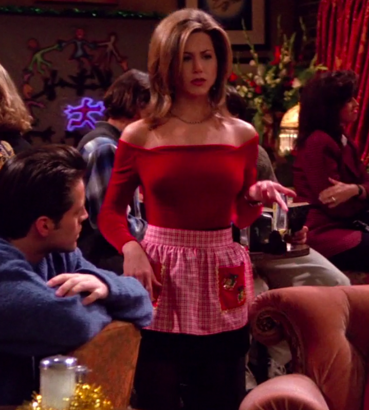 Rachel wearing booties, tights, a skirt, an apron, an off-the-shoulder long-sleeve shirt, and a necklace