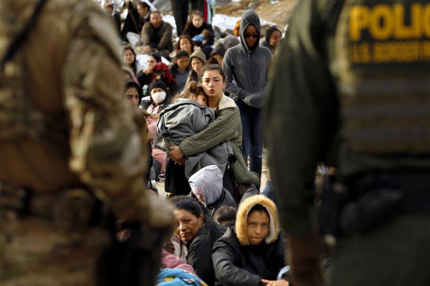 U.S. border, United States-May 11, 2023-U.S. border patrol agents make contact with migrants hoping to cross into the United States from Tijuana, Mexico on May 11, 2023. Some migrants have been waiting a week in an area south of the second border wall in anticipation of a change in immigration policy, Title 42, which may allow them to apply for asylum. U.S. border patrol agents give out one bottle of water and one granola bar to each person. There are approximately 500 people in this one camp. (Carolyn Cole / Los Angeles Times)