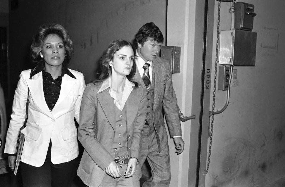 FILE - Accompanied by deputy U.S. Marshal John Brophy, Patricia "Patty" Hearst, center, leaves the Federal building on April 12, 1976, in San Francisco, hours after her sentencing on a bank robbery conviction. The newspaper heiress was kidnapped at gunpoint 50 years ago Sunday, Feb. 4, 2024, by the Symbionese Liberation Army, a little-known armed revolutionary group. The 19-year-old college student's infamous abduction in Berkeley, Cali., led to Hearst joining forces with her captors for the 1974 bank robbery. Hearst, granddaughter of wealthy newspaper magnate William Randolph Hearst, will turn 70 on Feb. 20. (AP Photo, File)