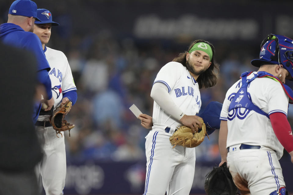 Toronto Blue Jays shortstop Bo Bichette passes a note to Matt Chapman as he stands on the mound during a pitching change during the sixth inning of the team's baseball game against the Tampa Bay Rays on Friday, Sept. 29, 2023, in Toronto. (Chris Young/The Canadian Press via AP)