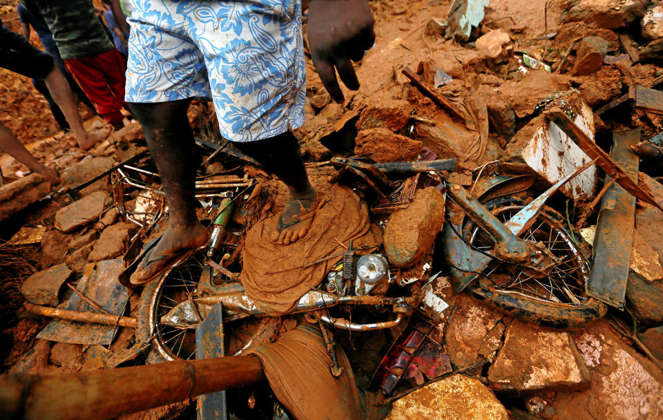 <p>A man stands on top of a damaged bike during a rescue mission at the site of a landslide in Bellana village in Kalutara, Sri Lanka, May 26, 2017. (Photo: Dinuka Liyanawatte/Reuters) </p>