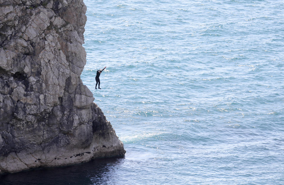 A person jumps into the sea from Durdle Door, near Lulworth, despite Dorset Council announcing that the beach was closed to the public after three people were seriously injured jumping off cliffs into the sea.