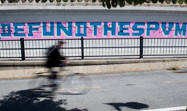 A person cycles by graffiti reading ‘Defund the SPVM’ (Montreal Police Department) in Montreal, Sunday, Aug 30, 2020.