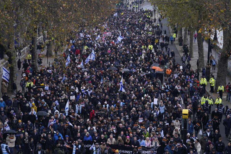 Manifestantes sostienen pancartas y banderas, incluida la de Israel, durante una marcha contra el antisemitismo en Londres, el domingo 26 de noviembre de 2023. (AP Foto/Alberto Pezzali)