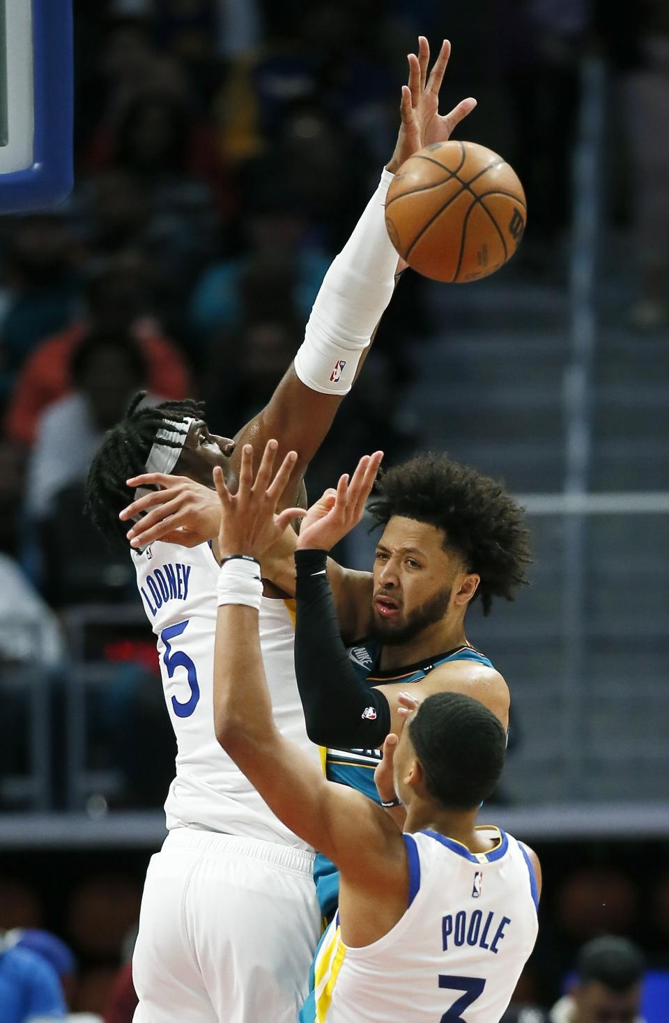 Detroit Pistons guard Cade Cunningham (2) passes the ball against Golden State Warriors center Kevon Looney (5) and guard Jordan Poole (3) during the first half of an NBA basketball game Sunday, Oct. 30, 2022, in Detroit. (AP Photo/Duane Burleson)