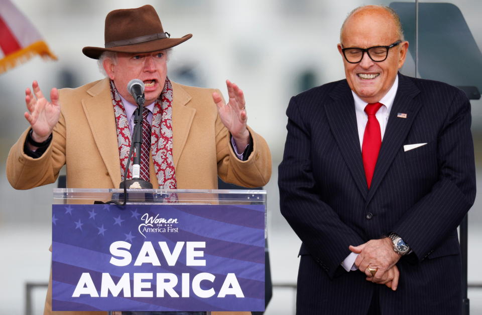 Attorney John Eastman, standing next to Rudy Giuliani, gestures as he speaks.